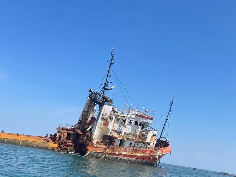 Large rusted shipwreck listing to one side in the ocean